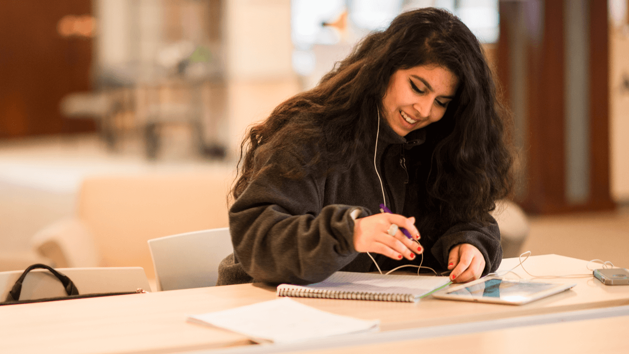 English student writing in campus center