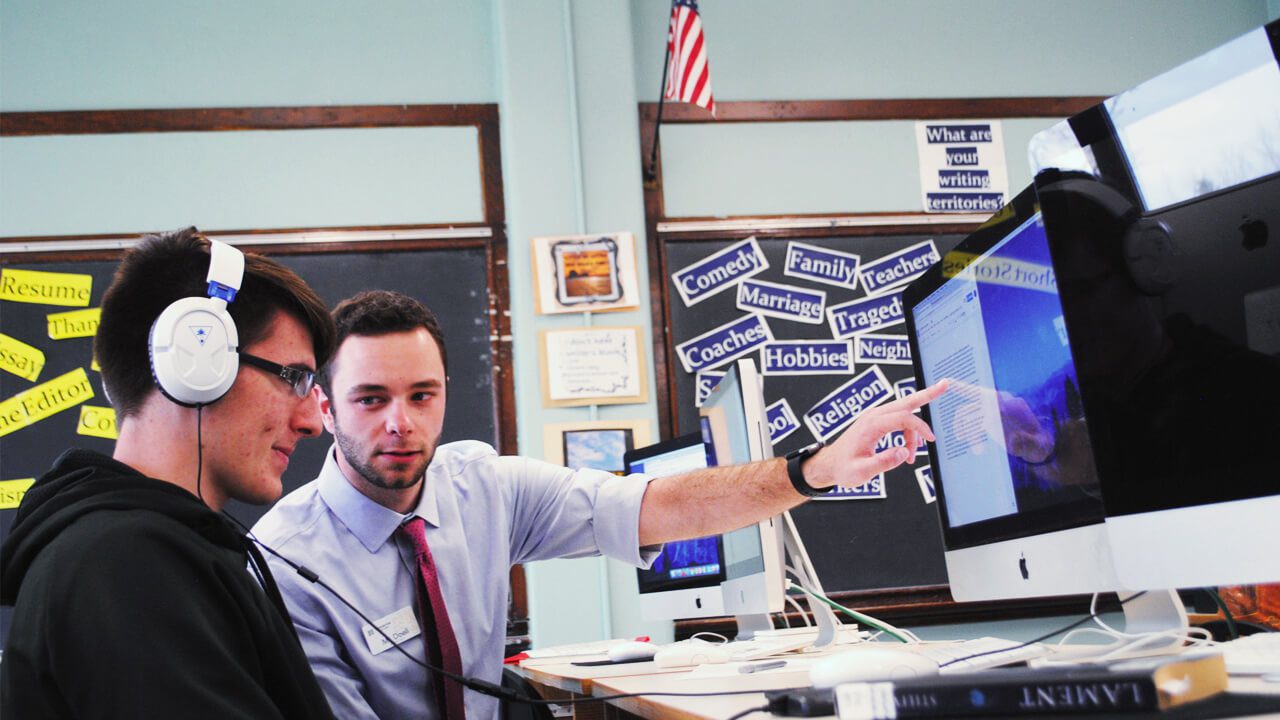 teacher working on essay with student at computer