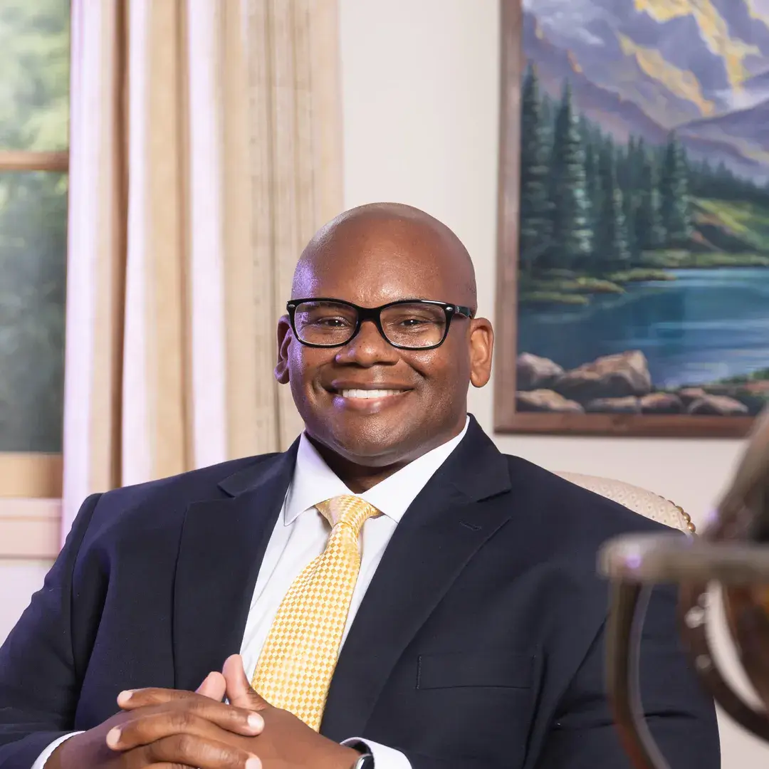 Houghton University President Wayne Lewis sitting at his desk.