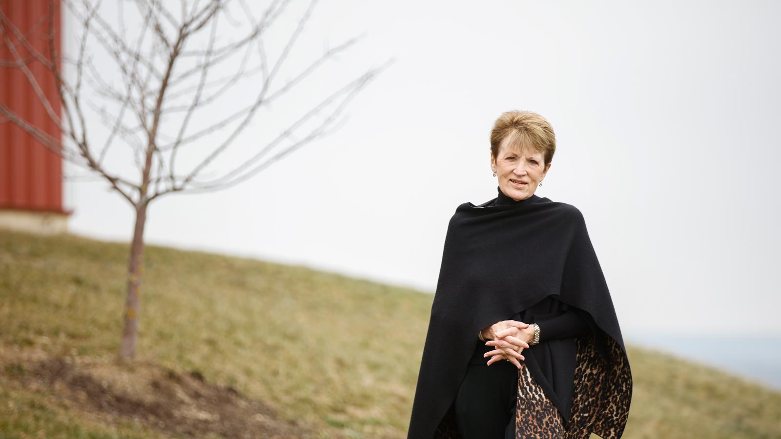 Shirley Mullen standing next to the Equestrian Center at Houghton College