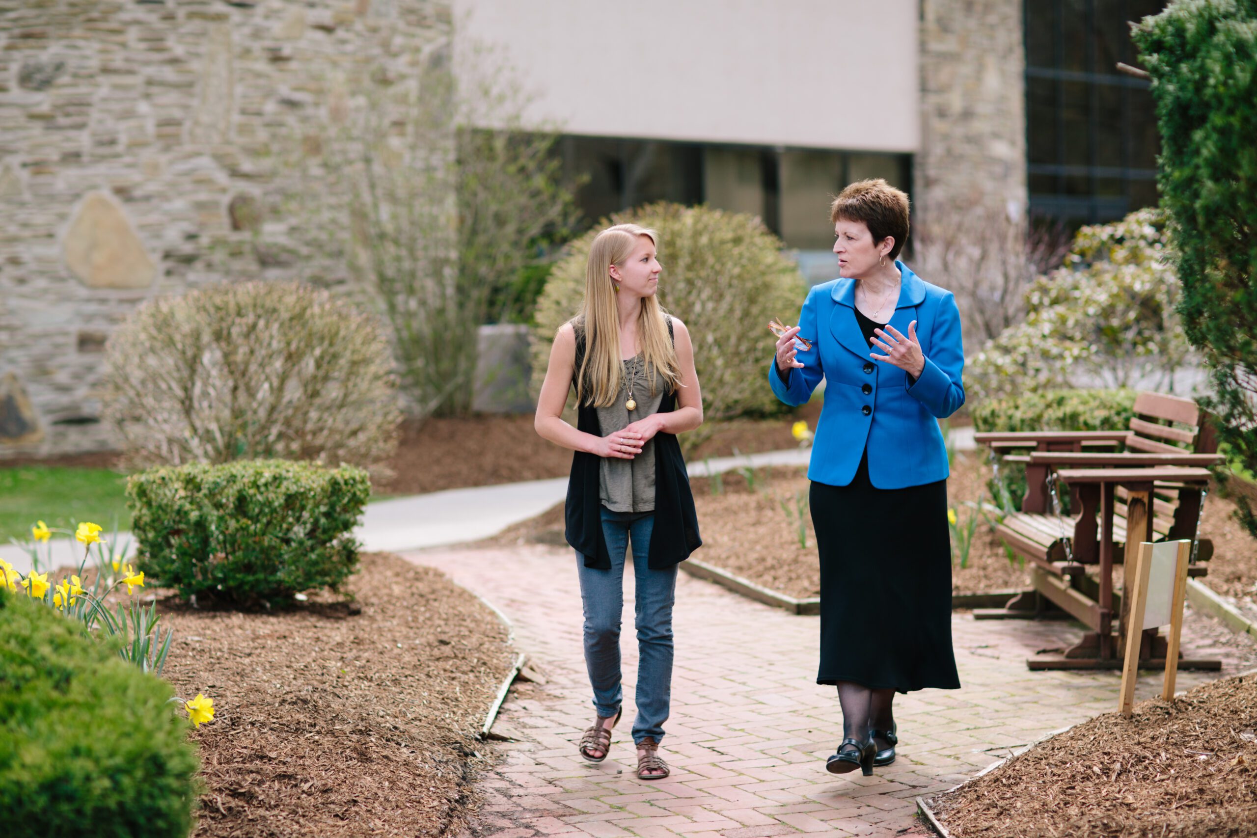 Shirley Mullen walking with student on Houghton's campus in the spring