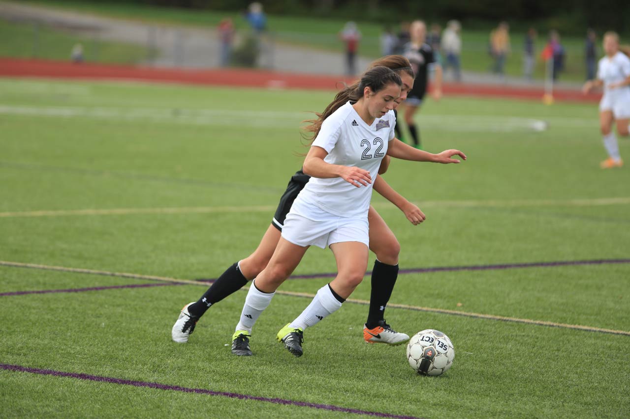 Women's soccer player racing down Burke field with the ball