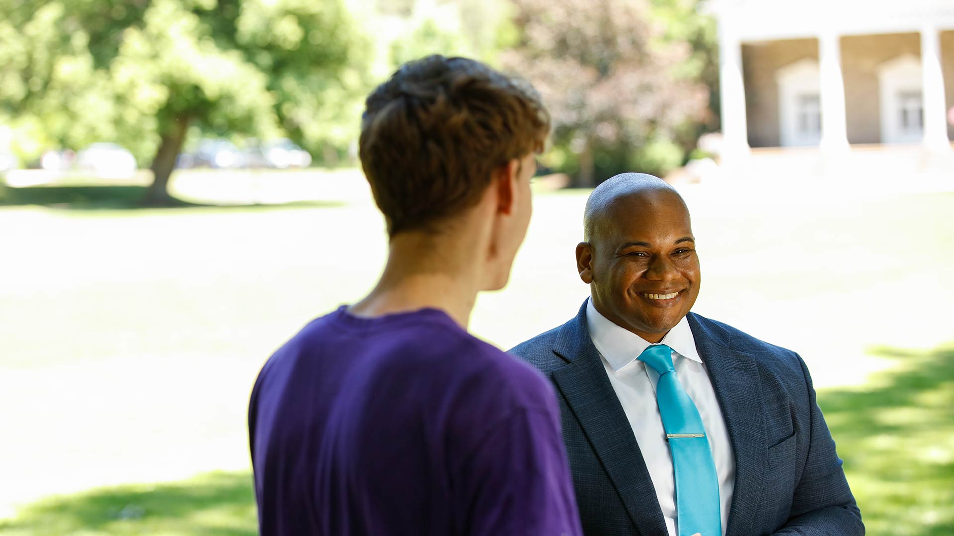 President Lewis speaking with a student in front of the Chapel Quad