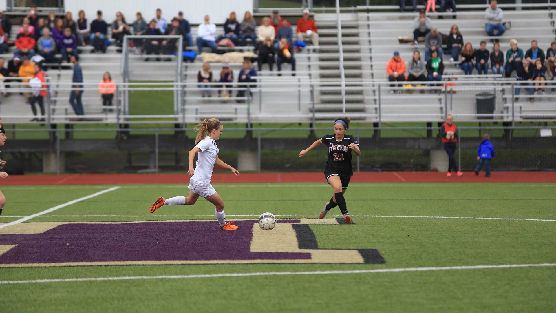 Houghton Women Soccer Player Running with ball across midfield line