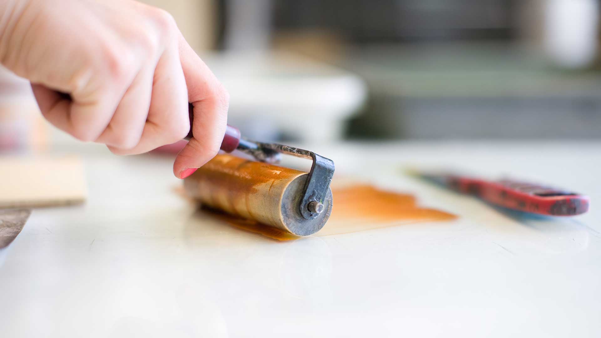 student using ink roller in printmaking studio