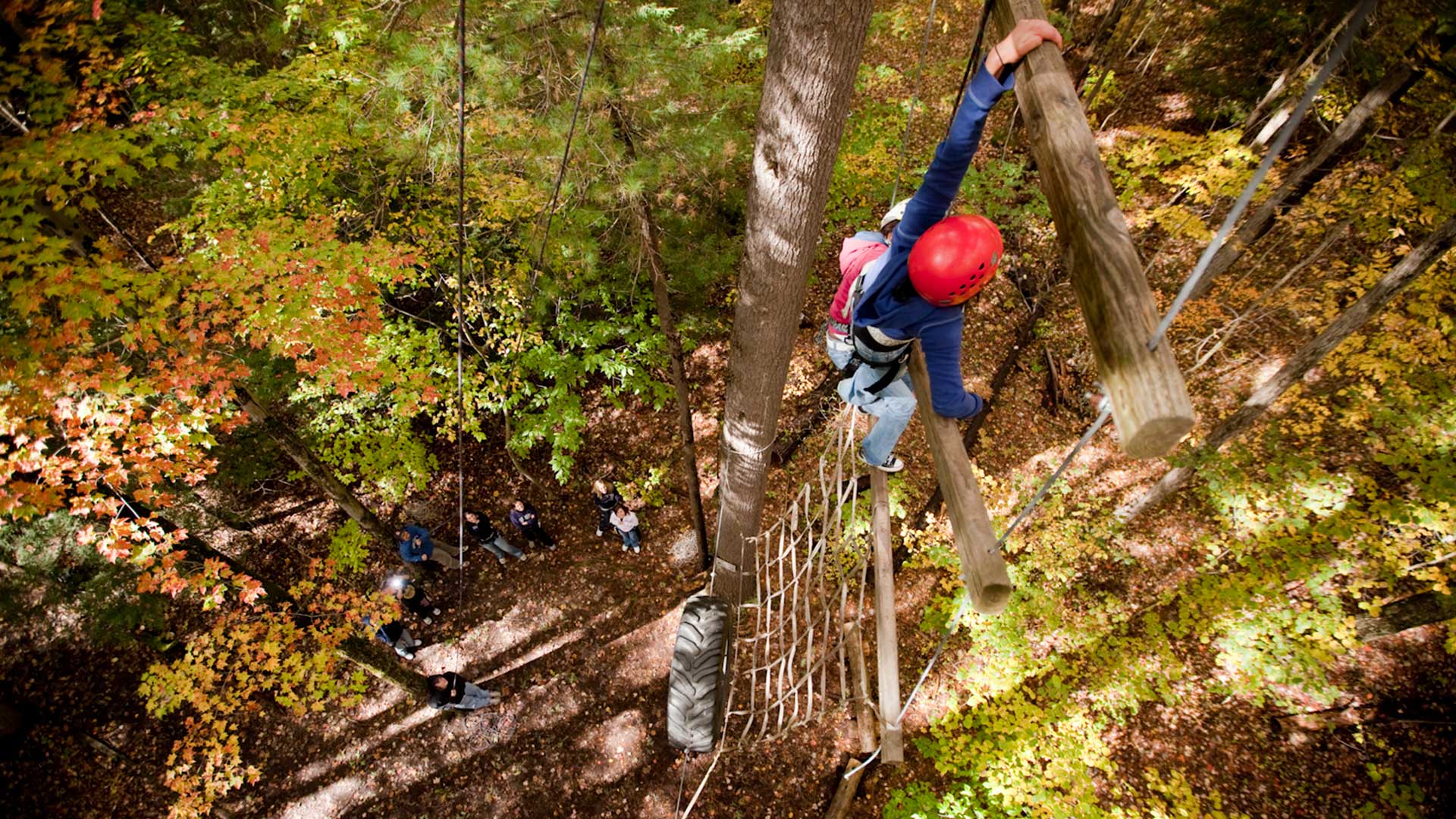 student climbing ropes course in the fall