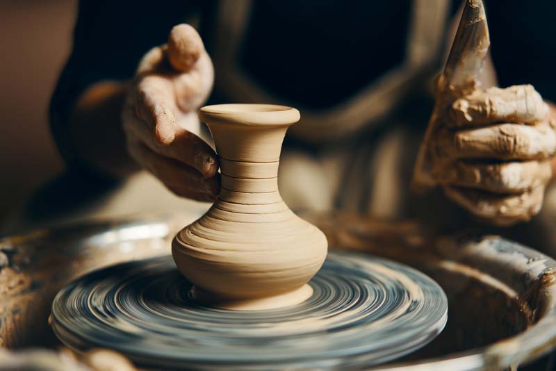 artist shaping a vase on a pottery wheel