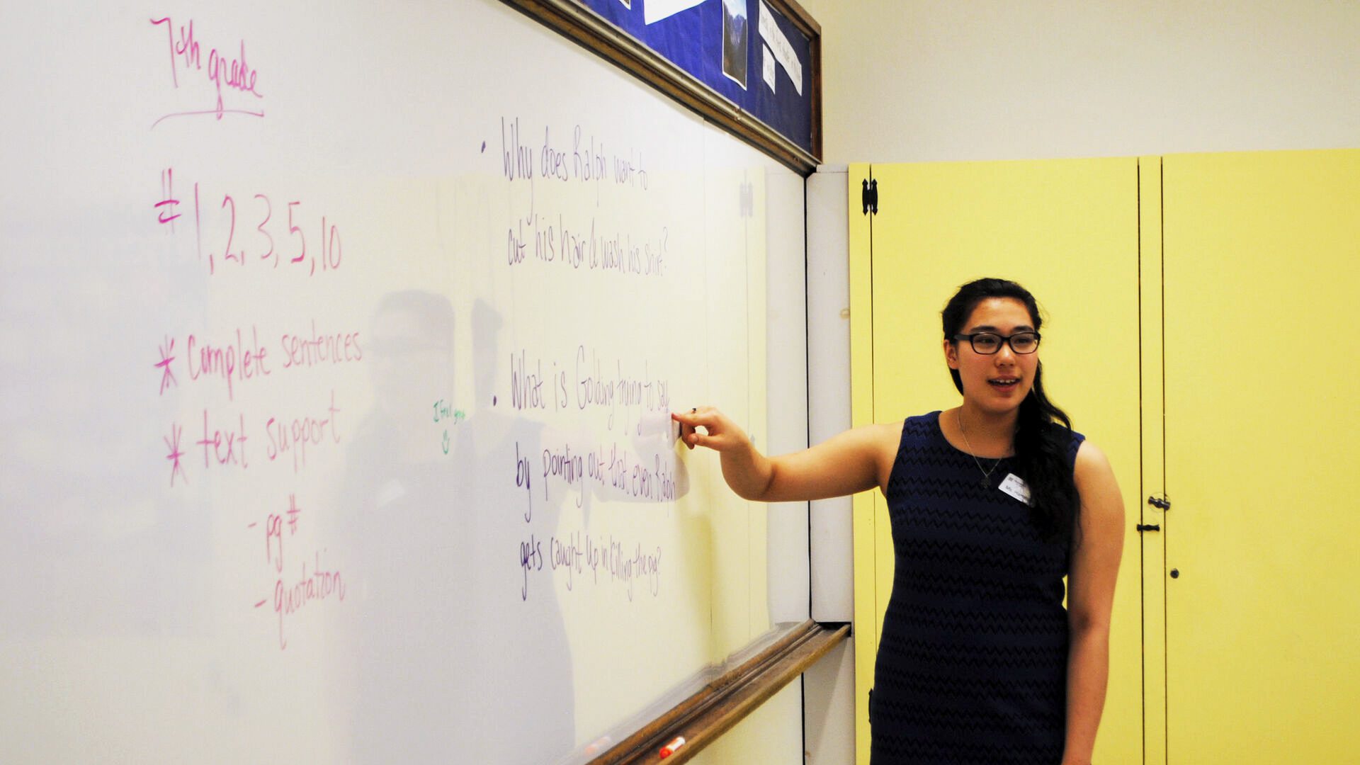 Student teaching pointing at dry erase board.