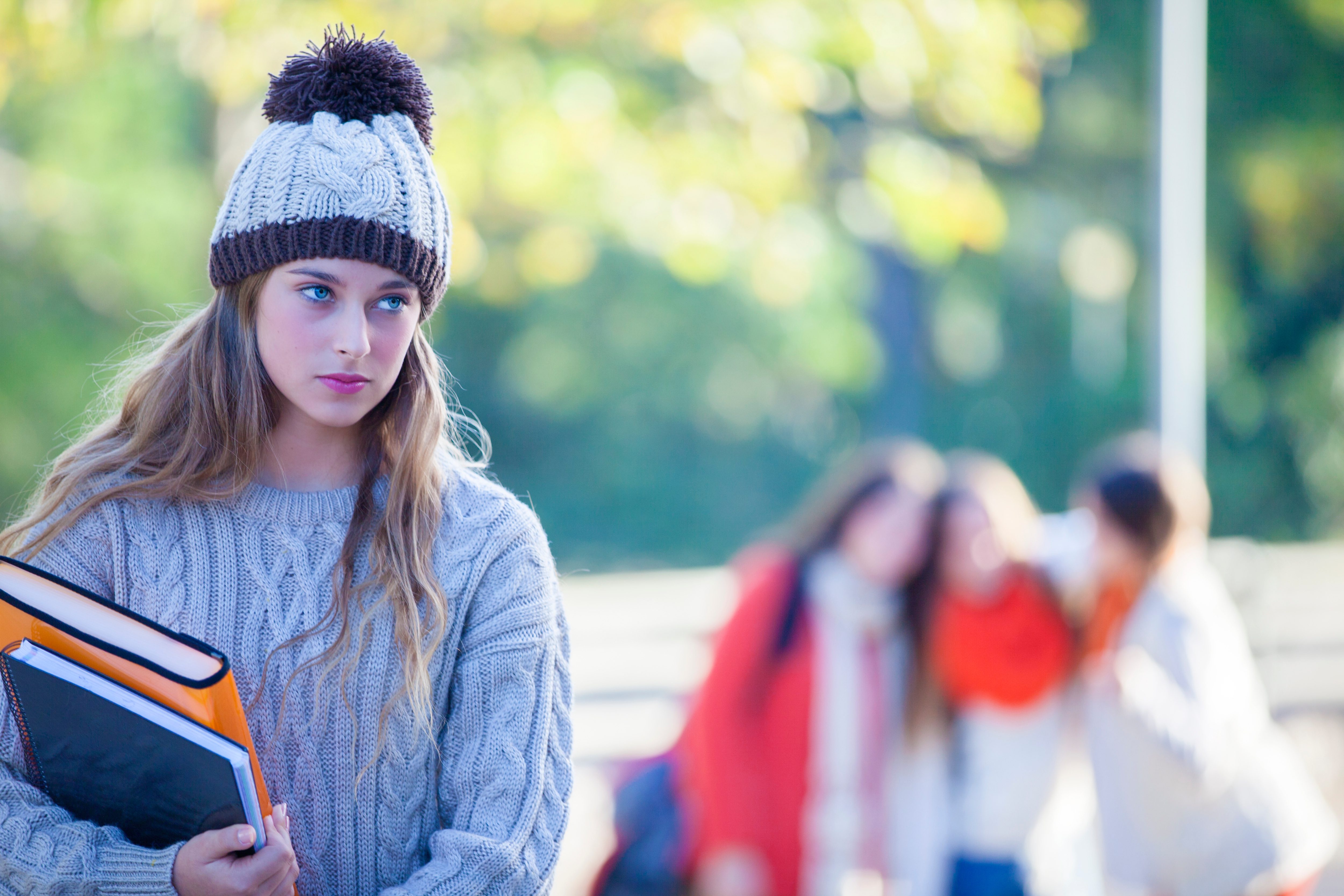 Student looking sad while students laugh in background