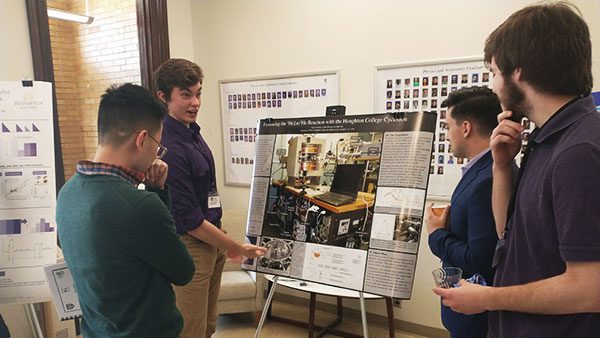 Student presenting their poster to a group of students