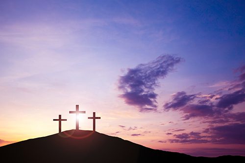 Three crosses on a hill during sunset,