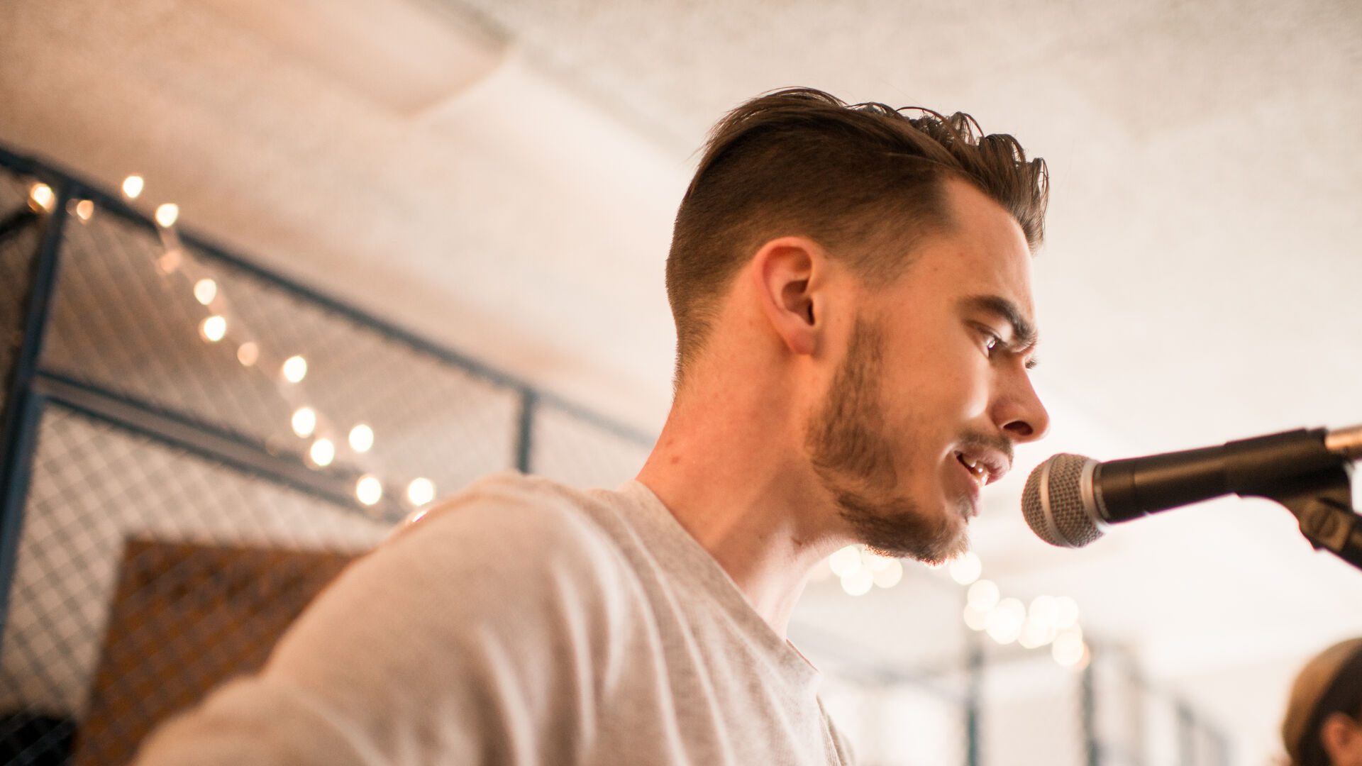 Student singing into microphone while playing guitar