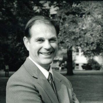 Black and white photograph of President Chamberlain standing in campus courtyard.