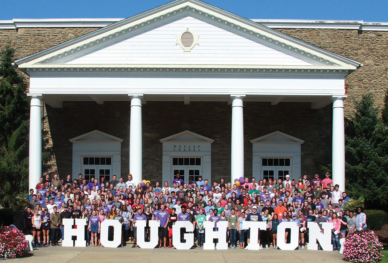 Large crowd of students posing for photo with large Houghton letters outside of chapel.