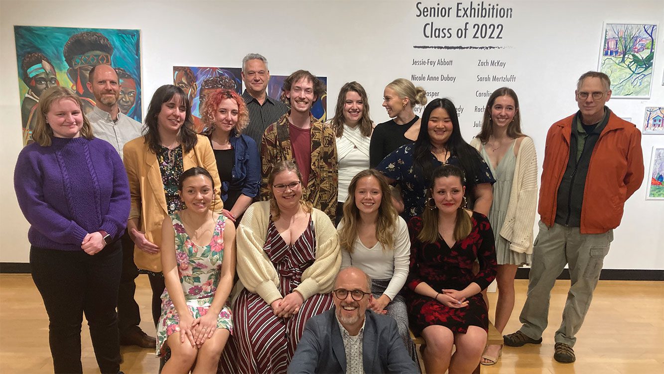 Art students and professors posing for photo in gallery.
