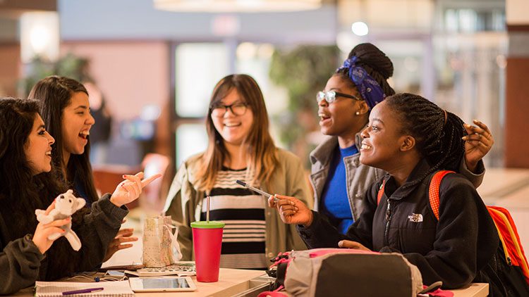 Students around a table laughing and talking.