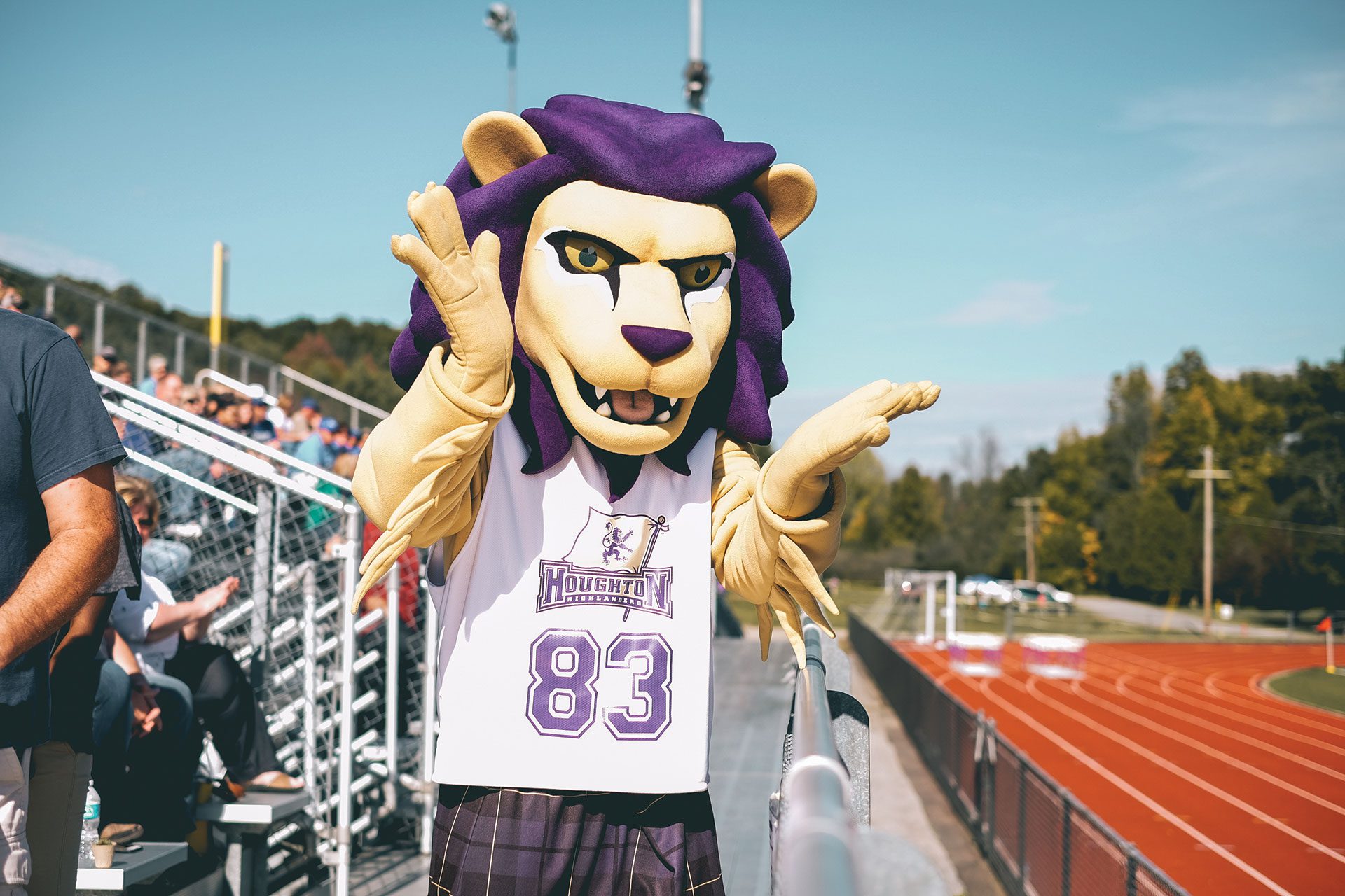 Luckey lion mascot raising hands in celebration on outdoor track.