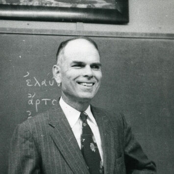 Black and white photograph of President Paine standing and smiling in classroom.