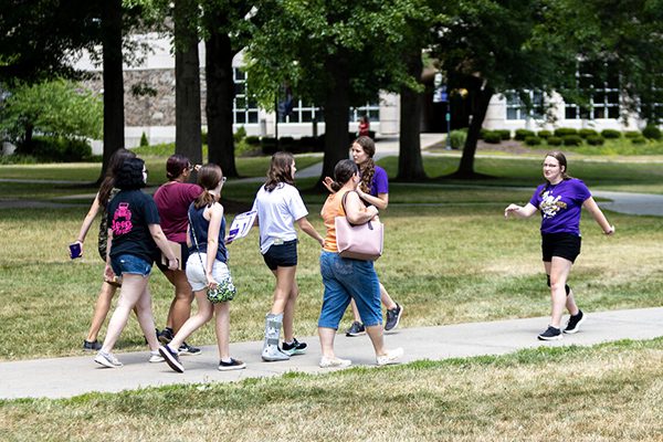 Two Houghton students in purple shirts leading a campus tour on Passport Day.