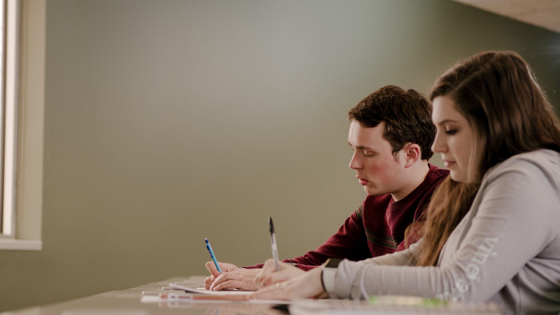 Two students sitting in business class taking notes.