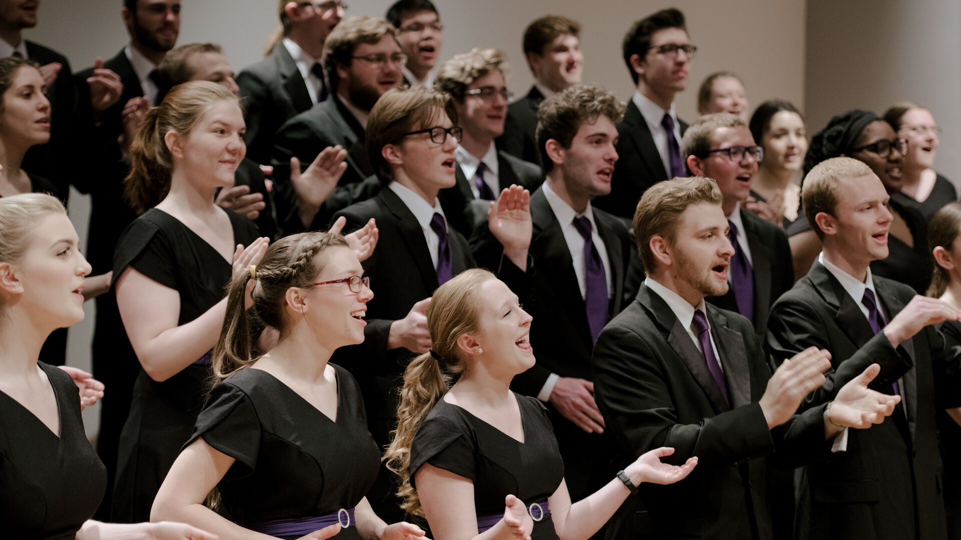 Houghton University's college choir dressed in black singing and clapping.