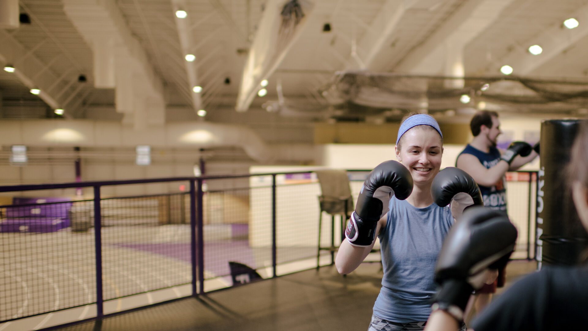 Student wearing boxing gloves doing martial arts with another student.