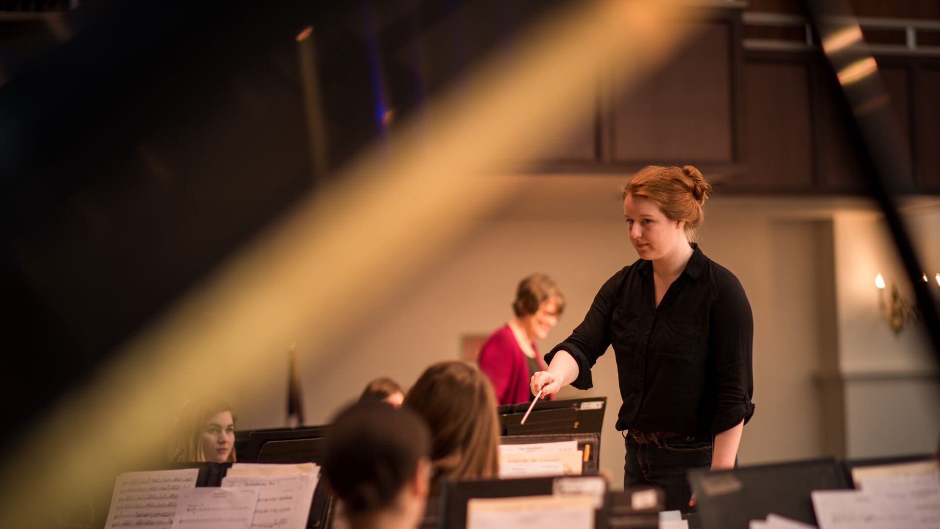 Student standing and conducting an orchestra.