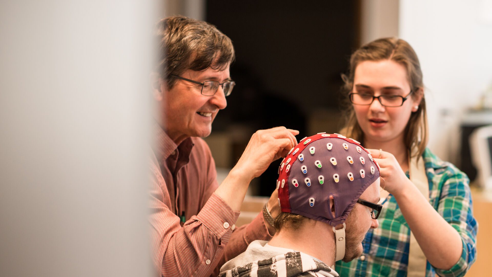 Houghton psychology students and professor putting measuring device on student's head.