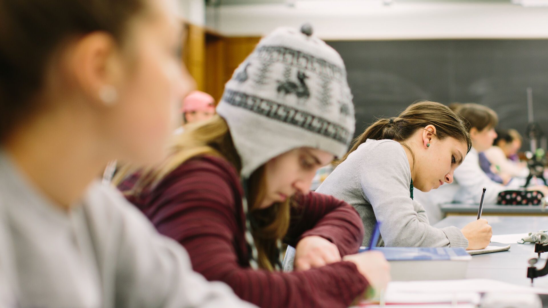 Student sitting together at table writing notes in a notebook.