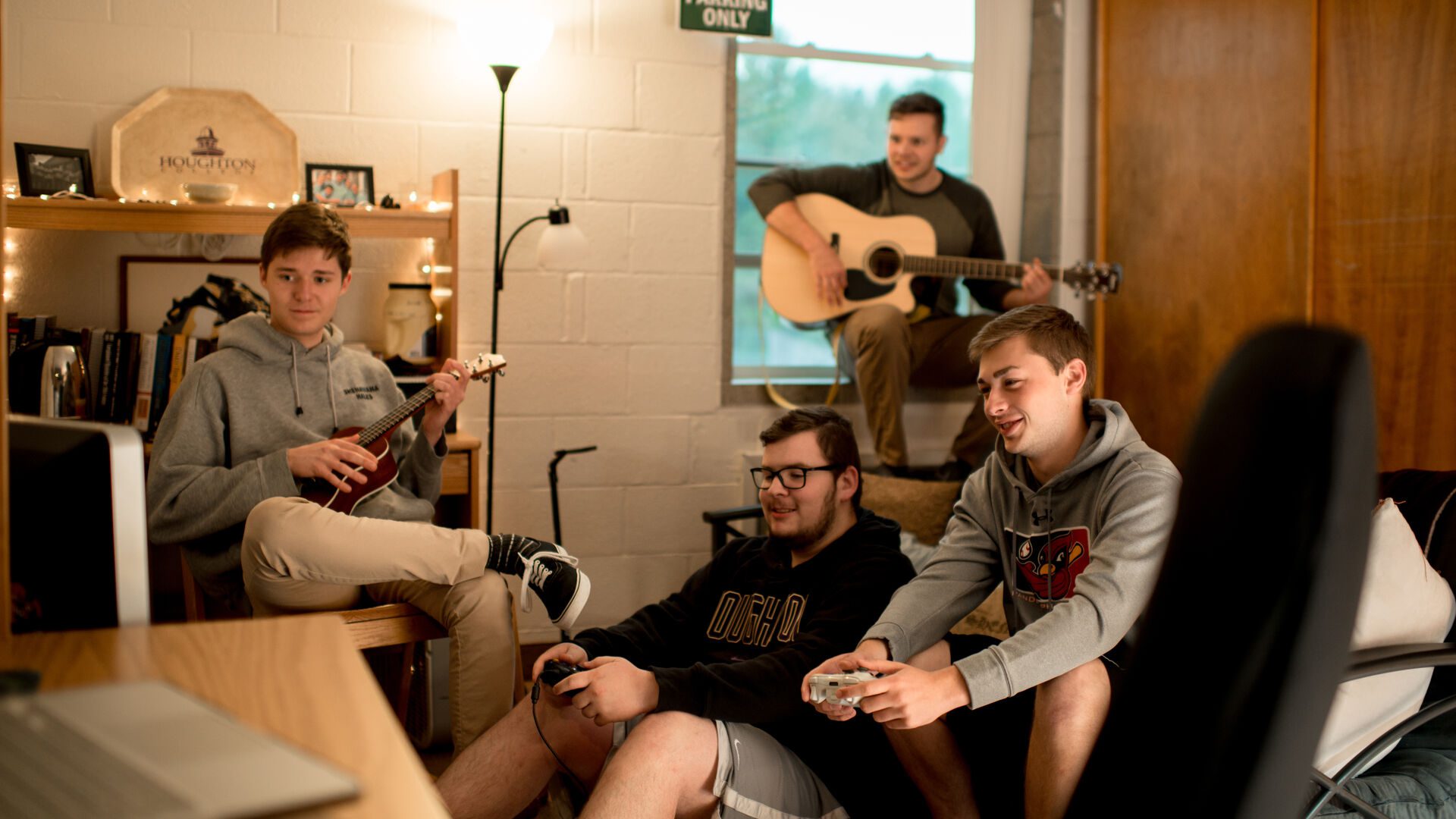 Group of Houghton students playing video games together in dorm room.