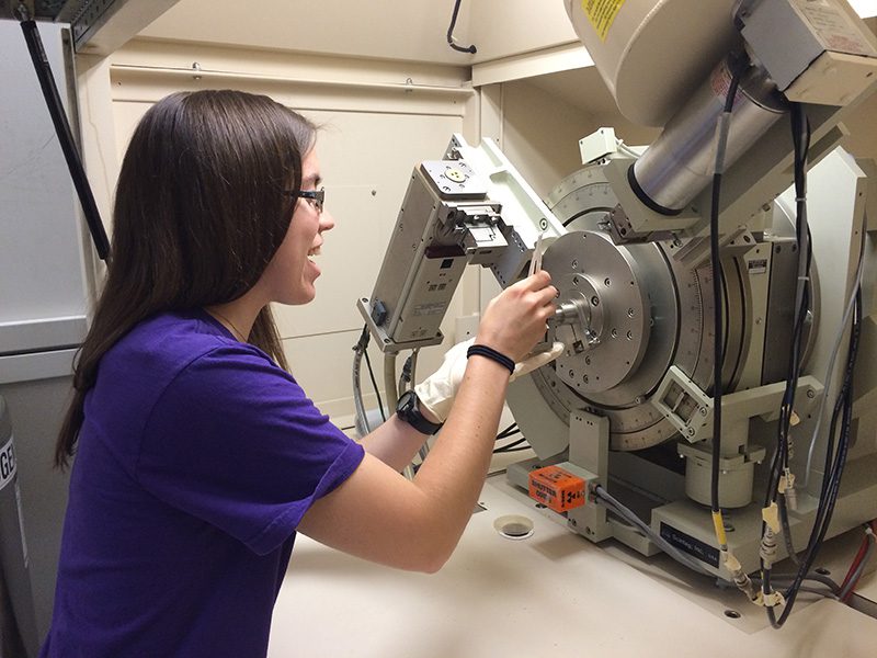 Houghton student Maggie Kirkland working with machine that studies thin sliver films at Cornell Center for Materials Research.