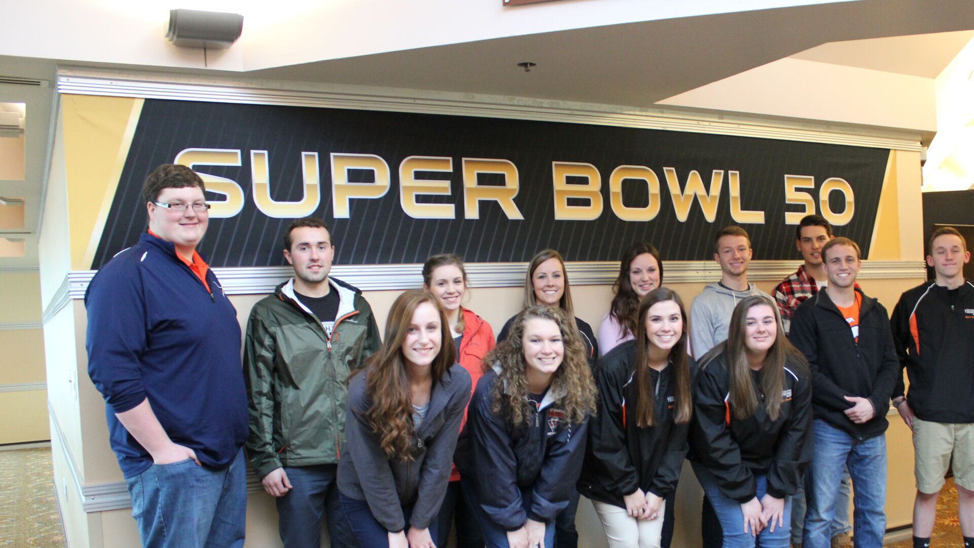 Data science students posed in front of the Super Bowl 50 sign.