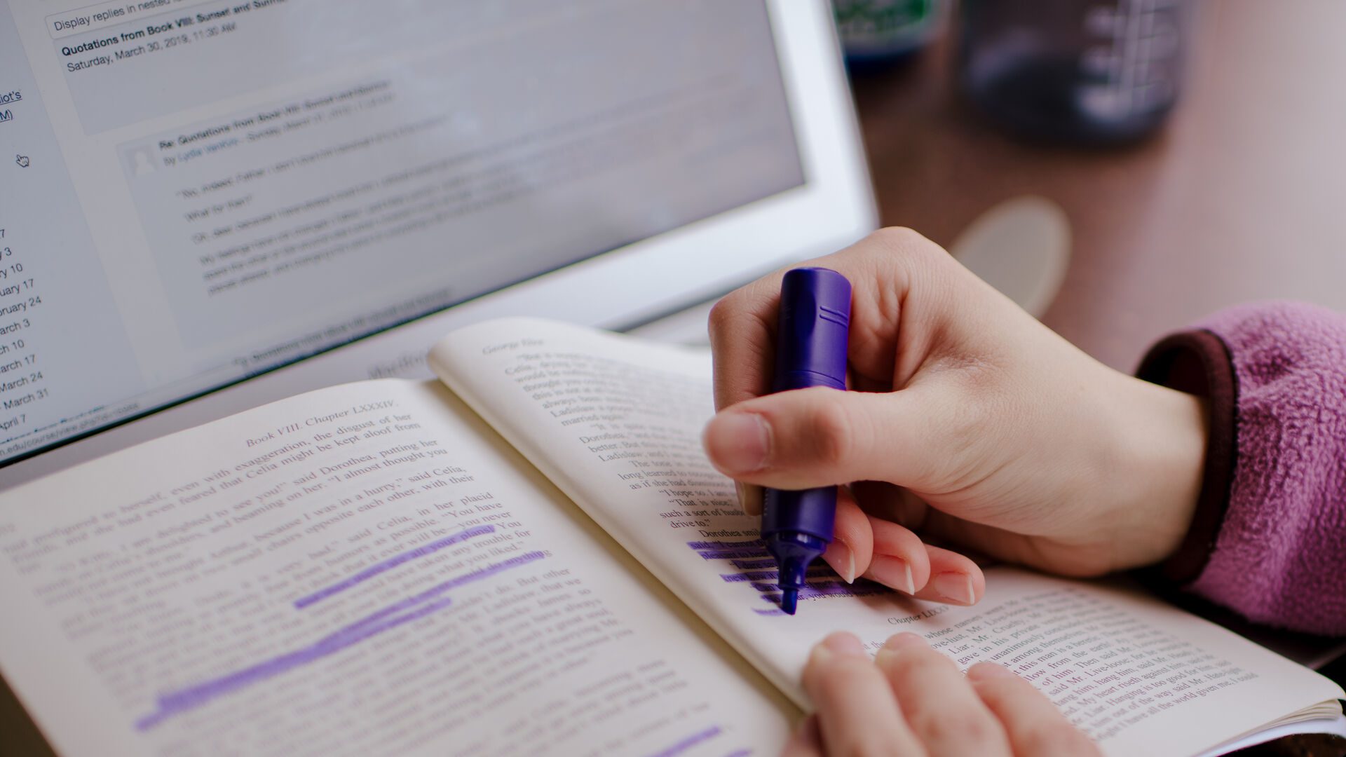 Student highlighting a book with purple highlighter.