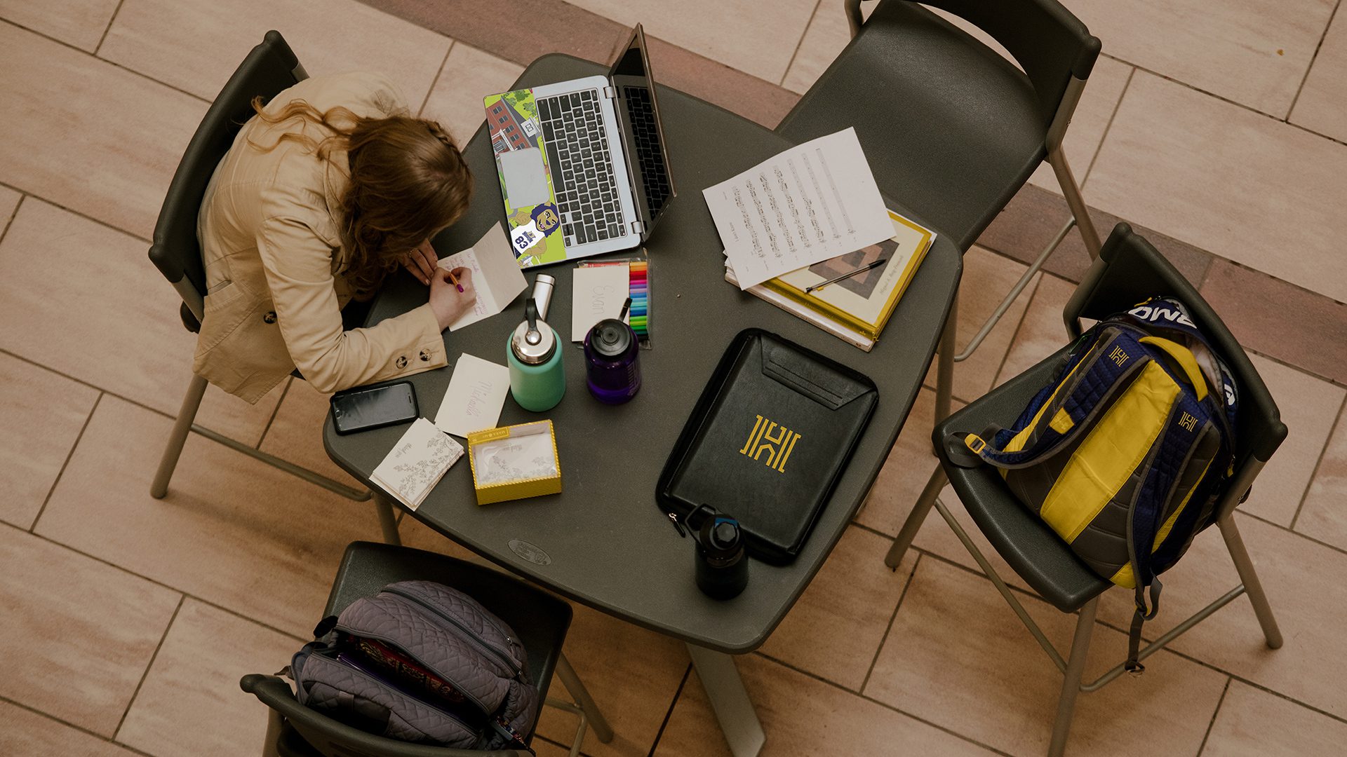 Overhead view of a student sitting at a table working at a laptop.