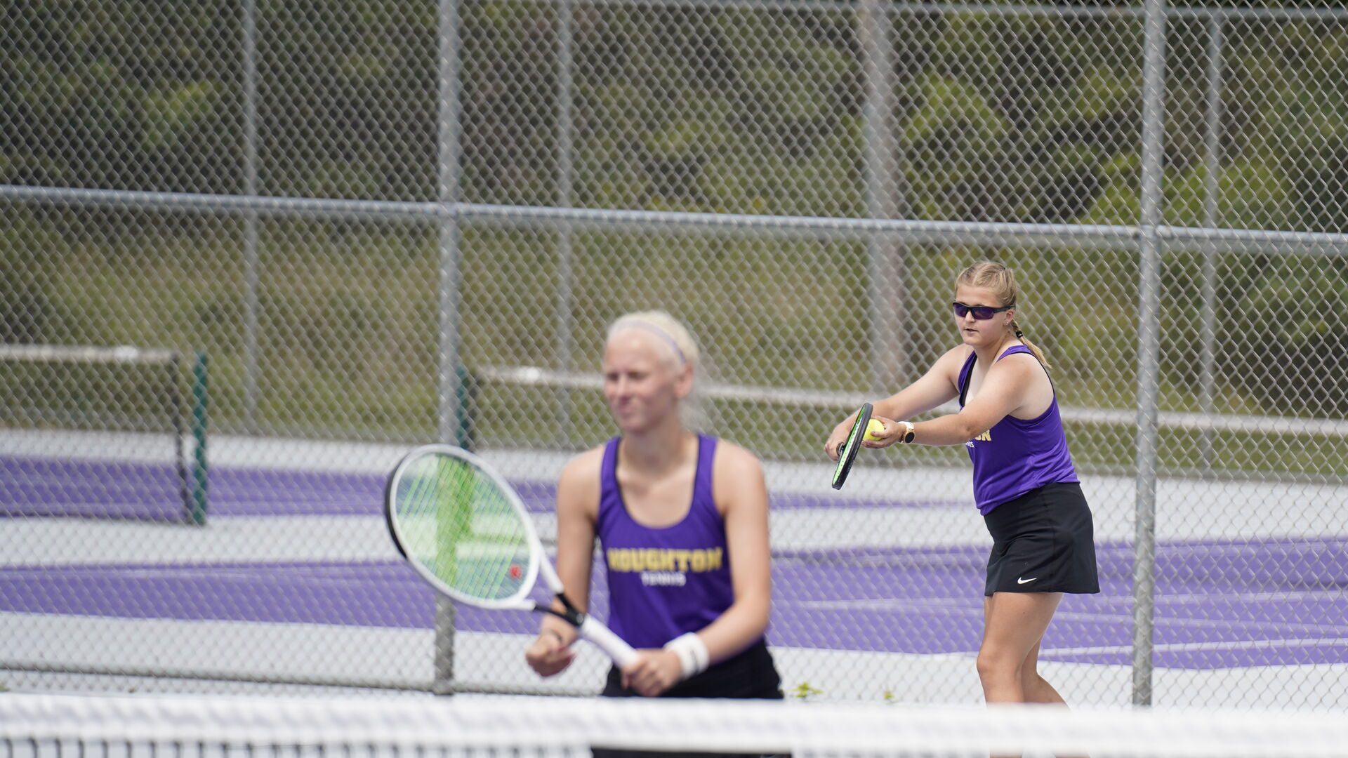 Houghton student preparing to serve during a tennis match.