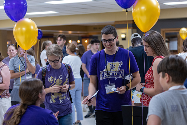 Students with Houghton gear at admission's table at Passport Day at Houghton Unviersity.