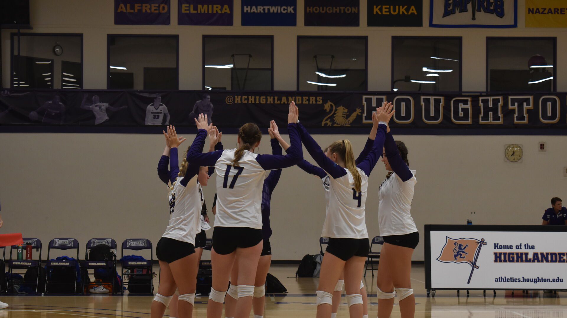 Houghton students standing together, hand to hand, gathering as team during a volleyball game.