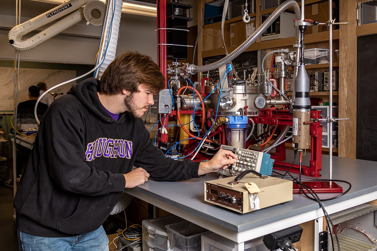 Houghton physics student working with instruments in physics lab.