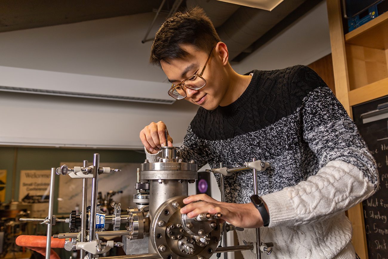 Houghton physics student working with instrument in physics lab.