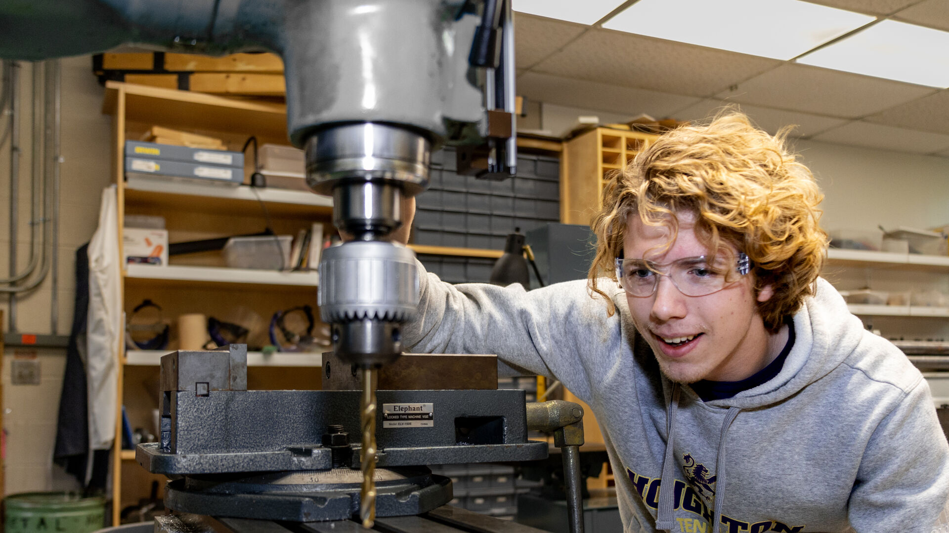 Houghton student using drill in physics lab.
