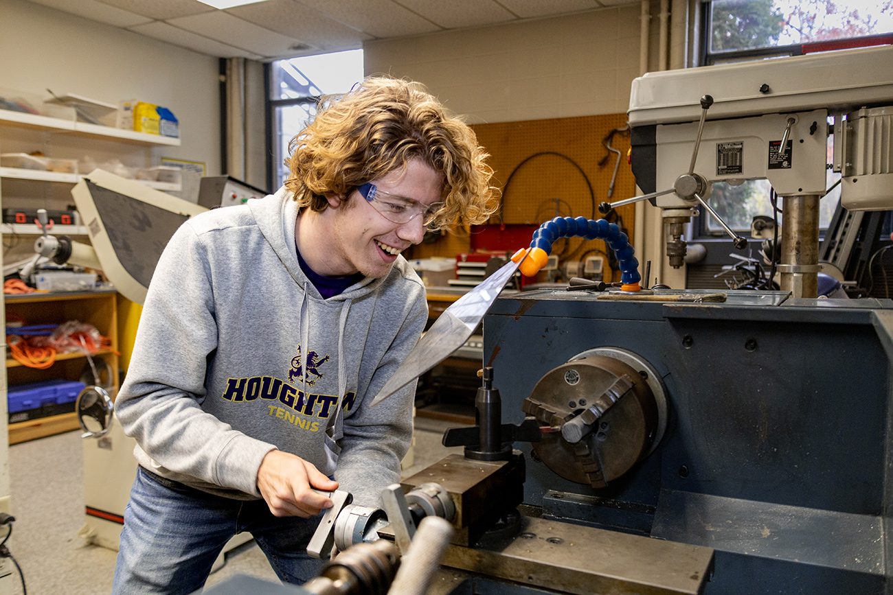 Houghton physics student working with machinery in physics machine lab.