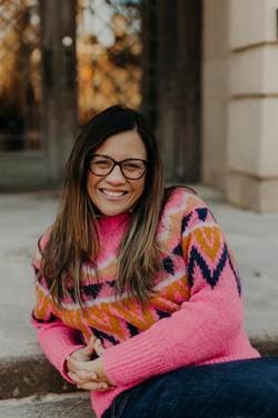 Marlena Graves leaning against outdoor steps with pink winter sweater.