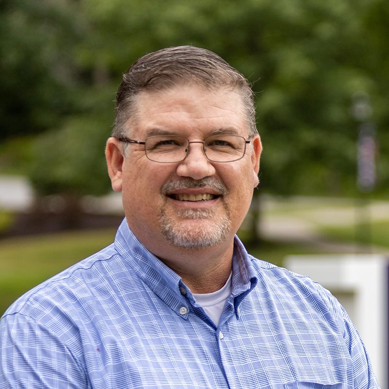 Craig Whitmore standing on Houghton's campus by the Houghton H.