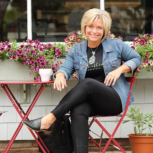 Belinda Bauman sitting in outdoor chair wearing jean jacket.