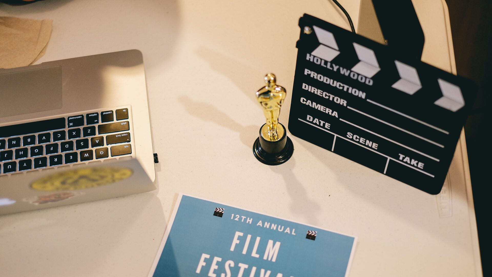 Table set-up with oscar replica, clapperboard, laptop and film festival flyer.