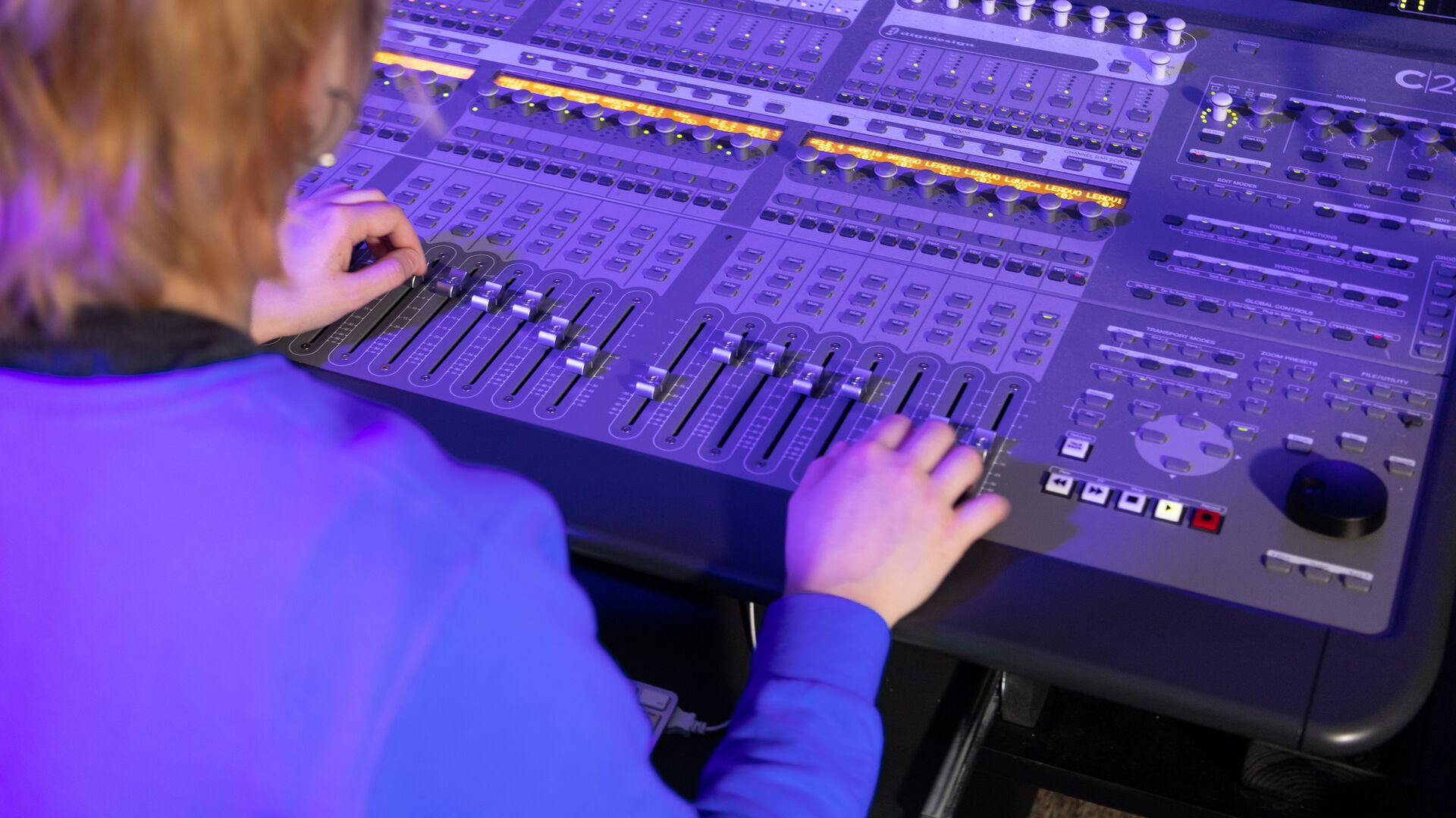 hands adjusting sliders on sound board