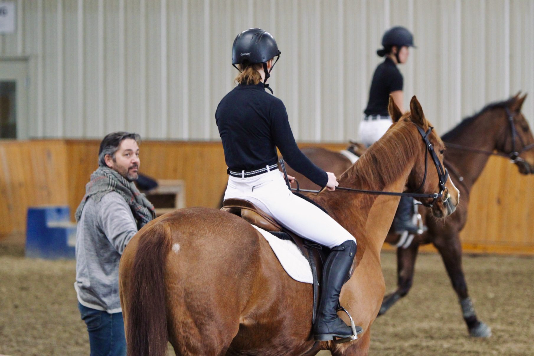 Clinician talking with students riding horses.