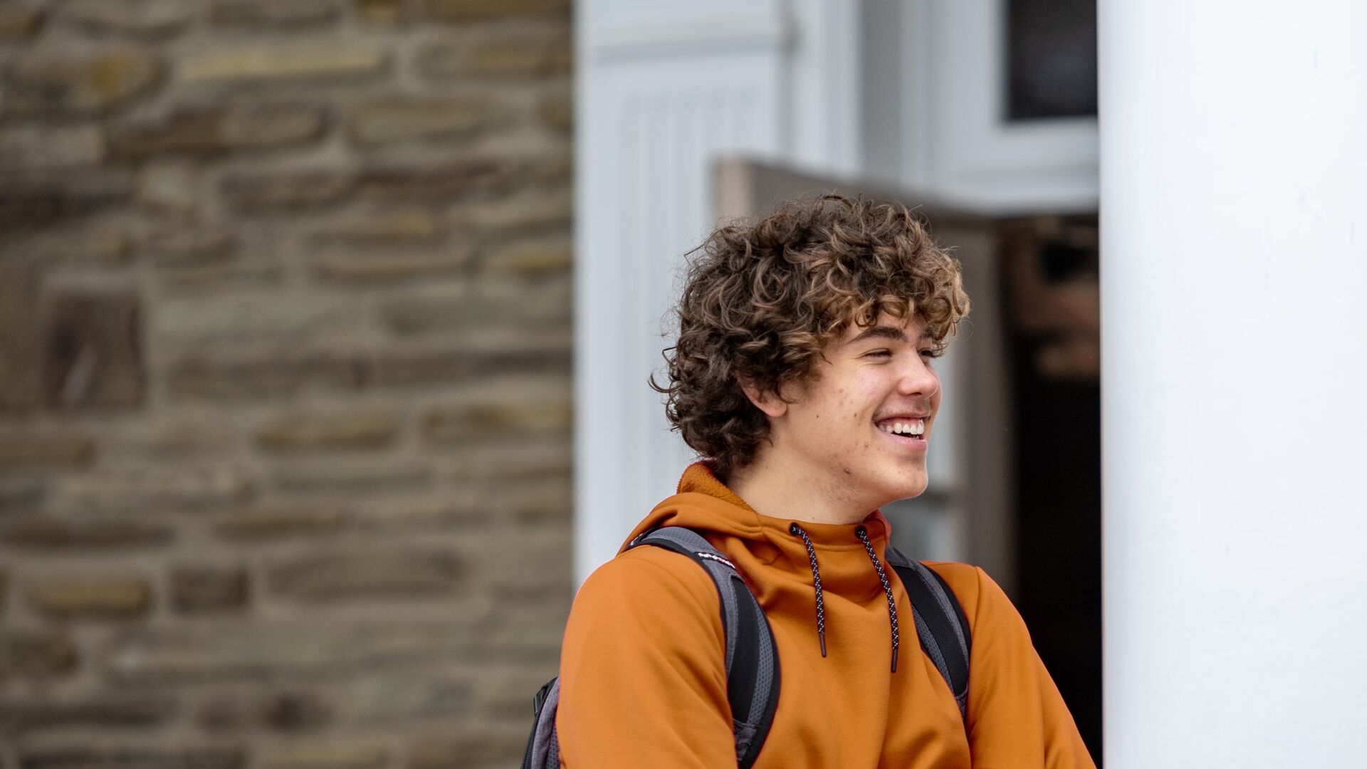 Houghton student smiling and standing on the steps outside of Chapel.