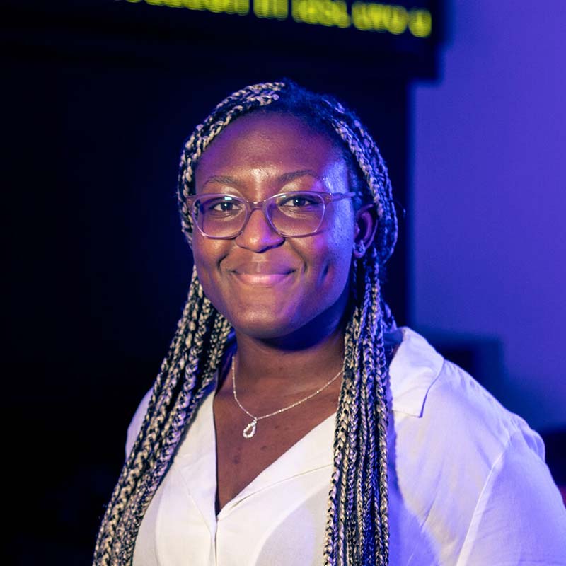 Ella Osuzoka, business student, standing in investment center smiling for portrait.