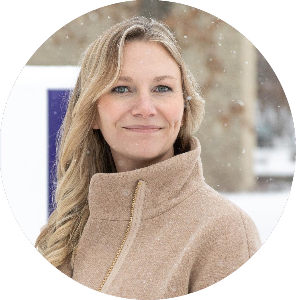 Heather Arnold standing in the front of the Houghton H on the campus lawn on a snowy day.